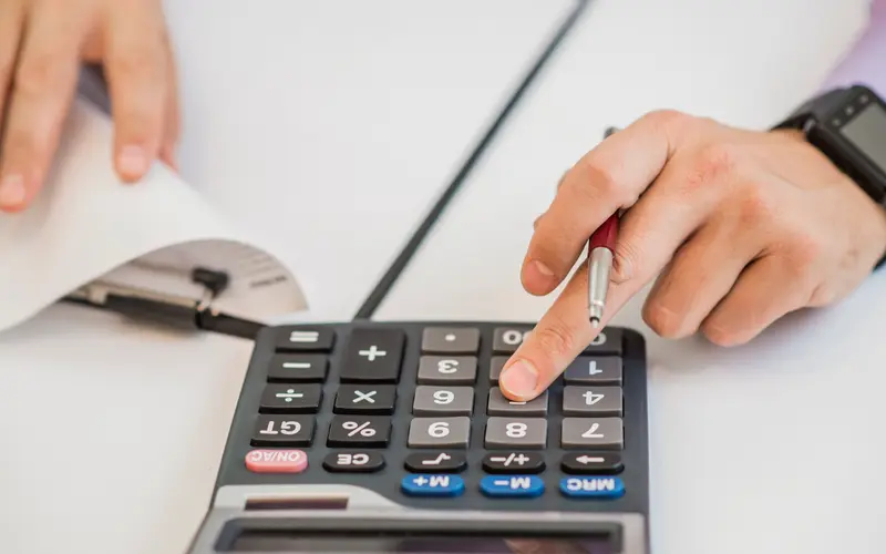 A businessman checking invoices with a calculator